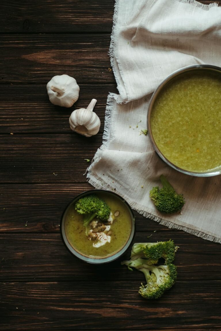A delicious and nutritious broccoli soup served with fresh garlic and herbs on a rustic wood table.