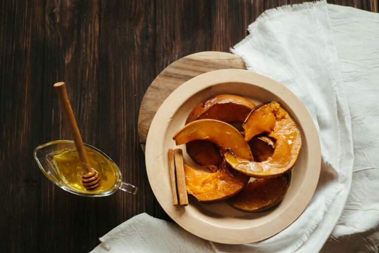 Delicious baked pumpkin slices with honey and cinnamon on a rustic wooden table.